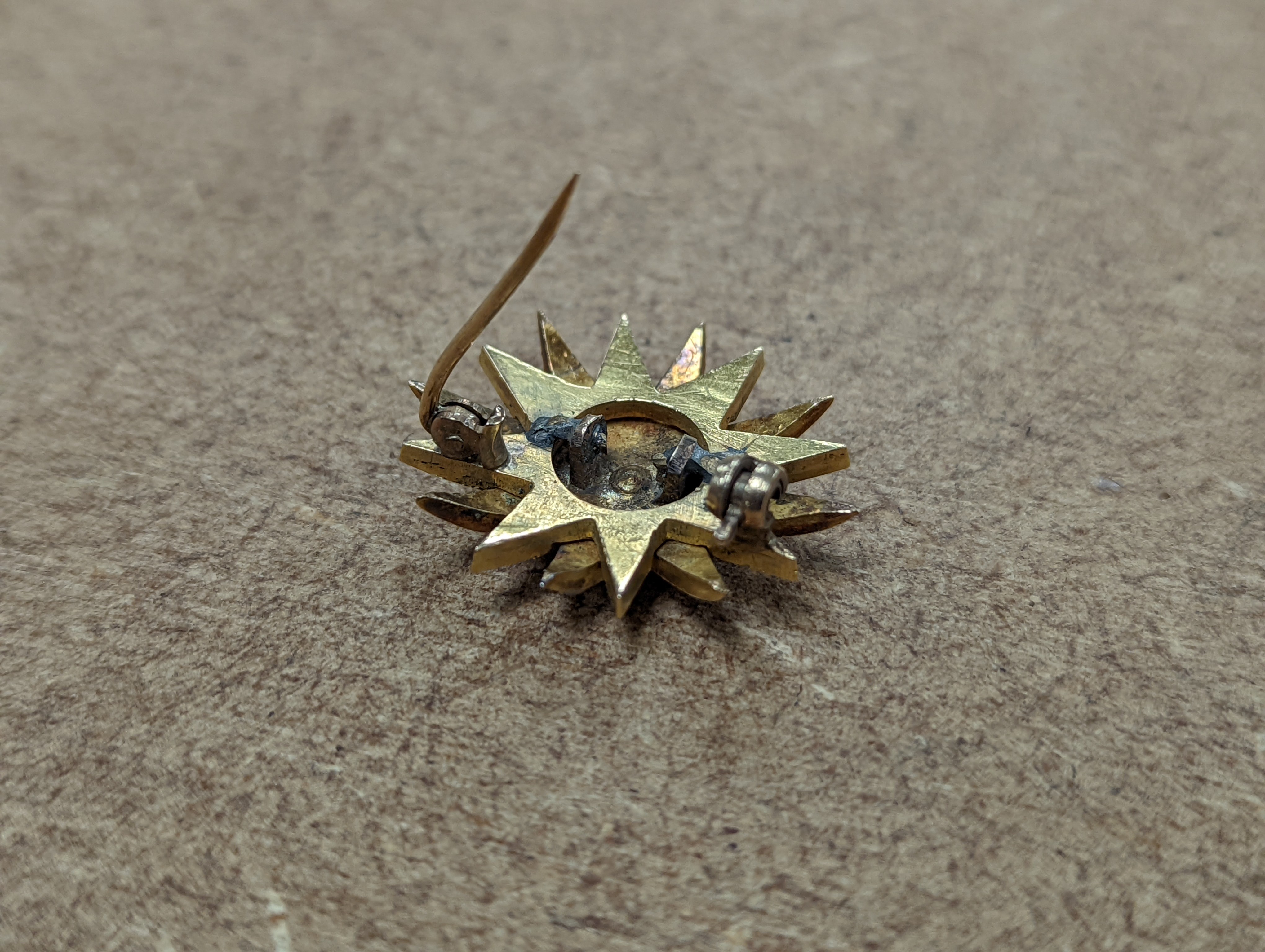 An Edwardian yellow metal, graduated split pearl and single stone diamond set starburst brooch(adapted?), 24mm, gross weight 6.5 grams.